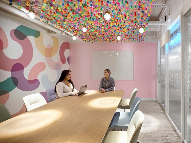 Fun Colourful conference room with organic shapes apainted mural and multi coloured pom-poms hanging down from the ceiling with lighting hanging among them