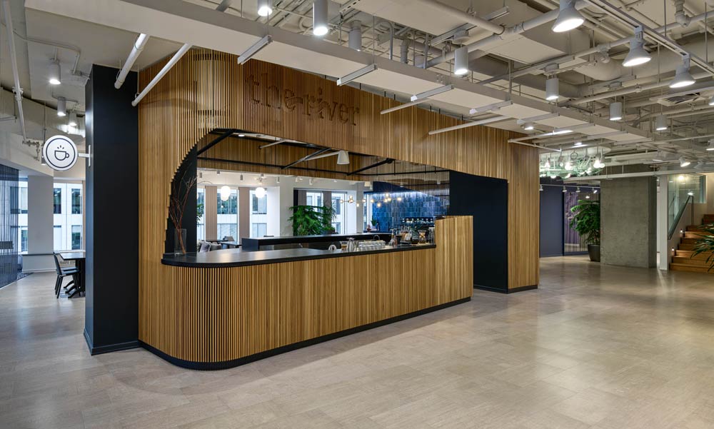 Coffee shop called 'The River' - is placed at the verey centre of the large open space. The base of the counter and the walls surrounding the bar are dressed in woodden slats,