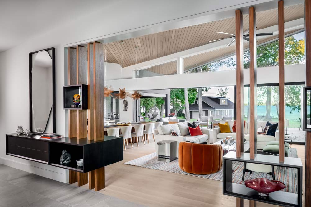 A view of the living and dining area from the hallway looking toward the lake and boathouse in the background