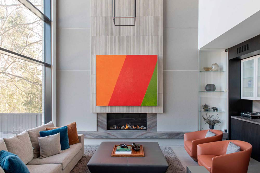 Focal point in the living room is a bright tri-coloured art work that hangs above the fire place, in front of which is the modern sofa and lounge chairs