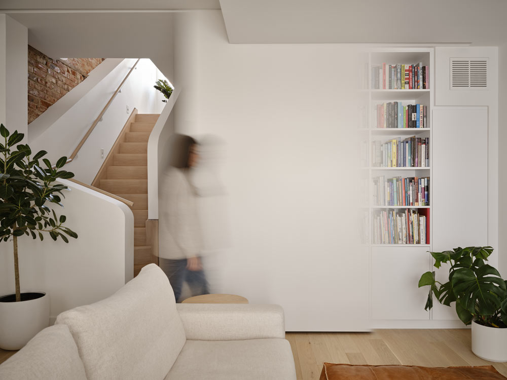 View from the living room towards the stunning staircase, and a person is walking at the bottom of the stairs