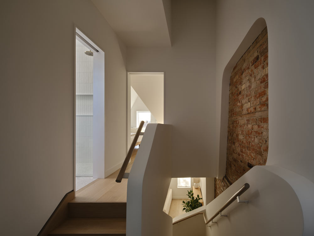 Beautiful curved lines of crisp white walls and railings in contrast to the piece of brick wall above the stairs