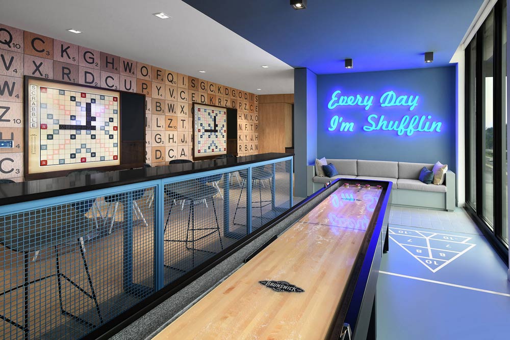 Another area meant for socializing, games and fun. The wall on the left is inspired by Scrabble letters with small round tables against it, and o the right there is a long bar top with stools facing a floor to ceiling window. On this side there is another play area with a large table