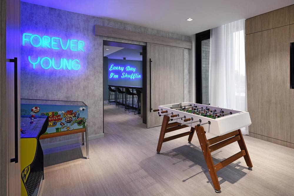 Another gaming area with table soccer and a few arcade games against the wall that had a fun neon signage that says 'forever young'