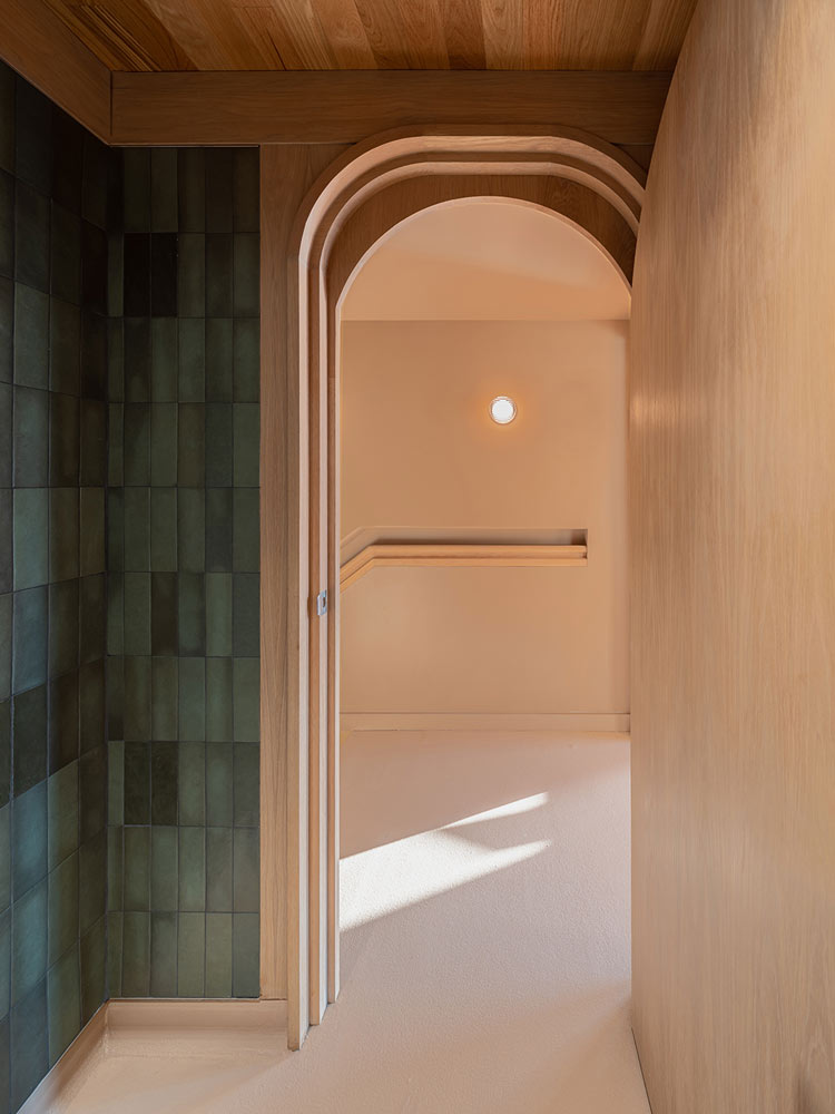 Arched door opening done in wood finish and beautiful green tile covers the wall to the left of the door