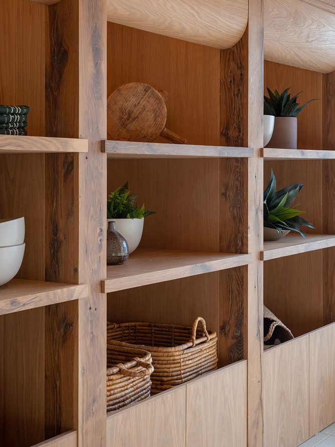 Wooden built in shelf displaying potted plants and wooden rustic pieces and woven baskets