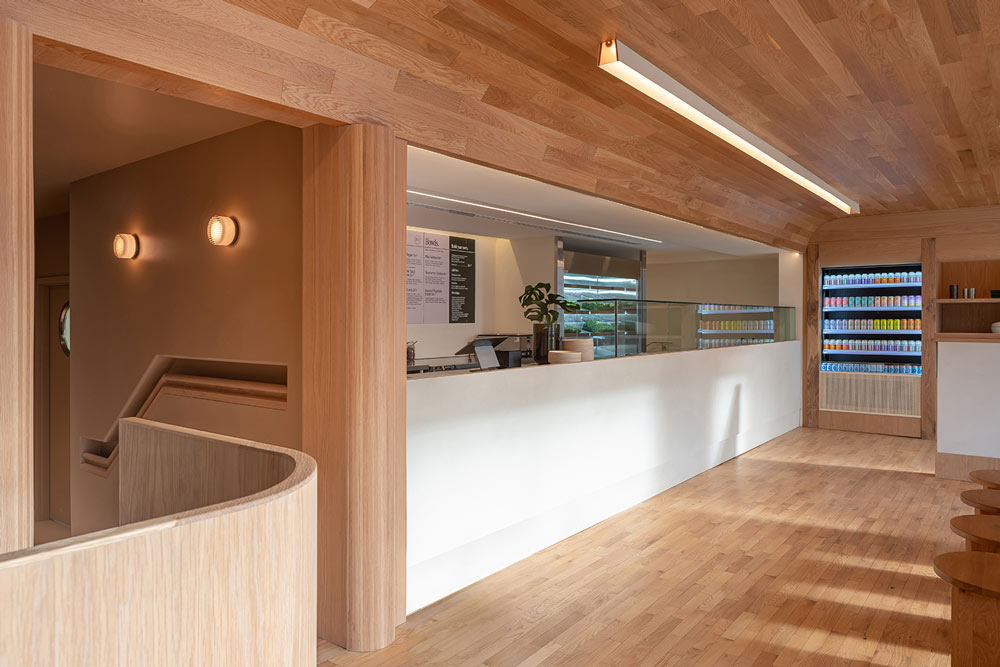 A view of the entire front counter and display section, looking in from the main entrance direction. The entire spaces is covered in natural wood, in contrast to the clean, white counter base
