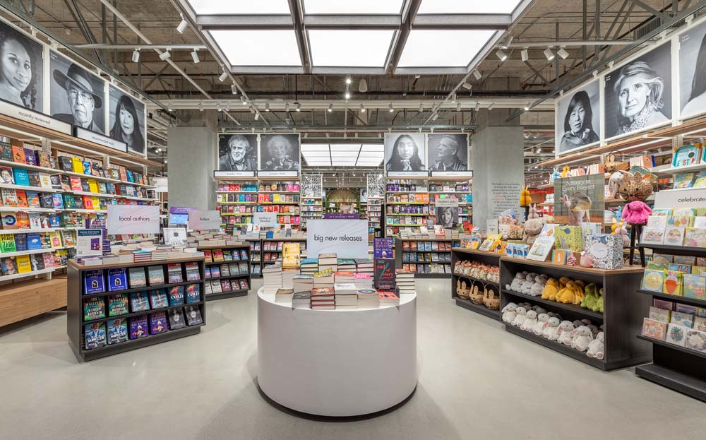Customers are welcomed by black-and-white photographs of celebrated culture-makers that adorn the wall fixture uppers. In the centre is a round display table for books and several floor book shelves arranged in a diagonal fashion throughout the space