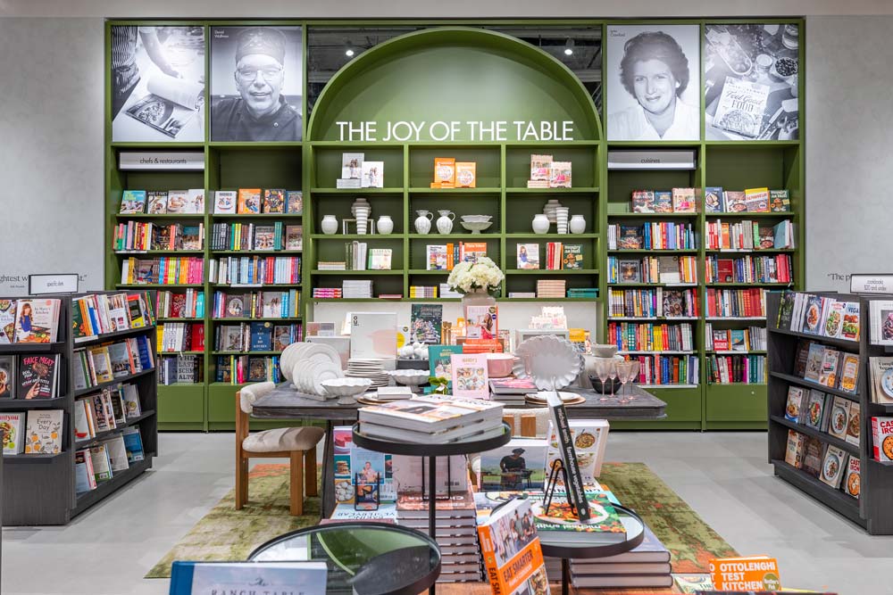 In the cooking section, a large green book shelf adorns the wall, with a beautifully arranged display table in front of it and more smaller book shelves on the sides